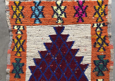 Alfombra boucherouite vintage vista de cerca, franjas naranjas y motivos de colores