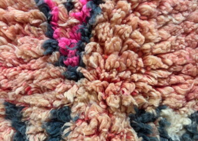 Alfombra marroquí Boujad New Works: primer plano del pelo largo de lana rosa salmón con franjas fucsia y gris antracita. Detalle.