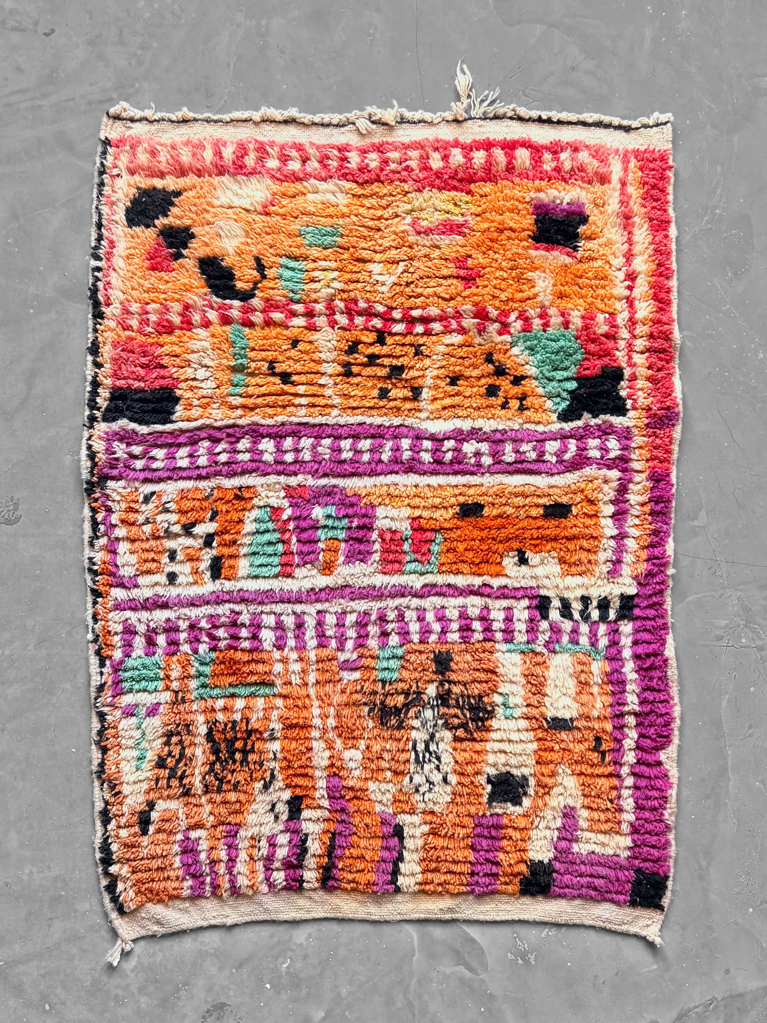 Boujad New Works Moroccan wool rug in orange, fuchsia and pink, with sea green, black and ecru signs and an ecru kilim end. Full view.