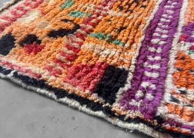 Boujad New Works Moroccan rug: edge in perspective with fuchsia border and black blocks. Detail.