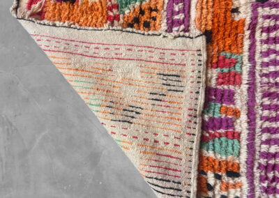 Boujad New Works Moroccan rug: folded corner showing the ecru woven back with pink and black stripes. Back detail.