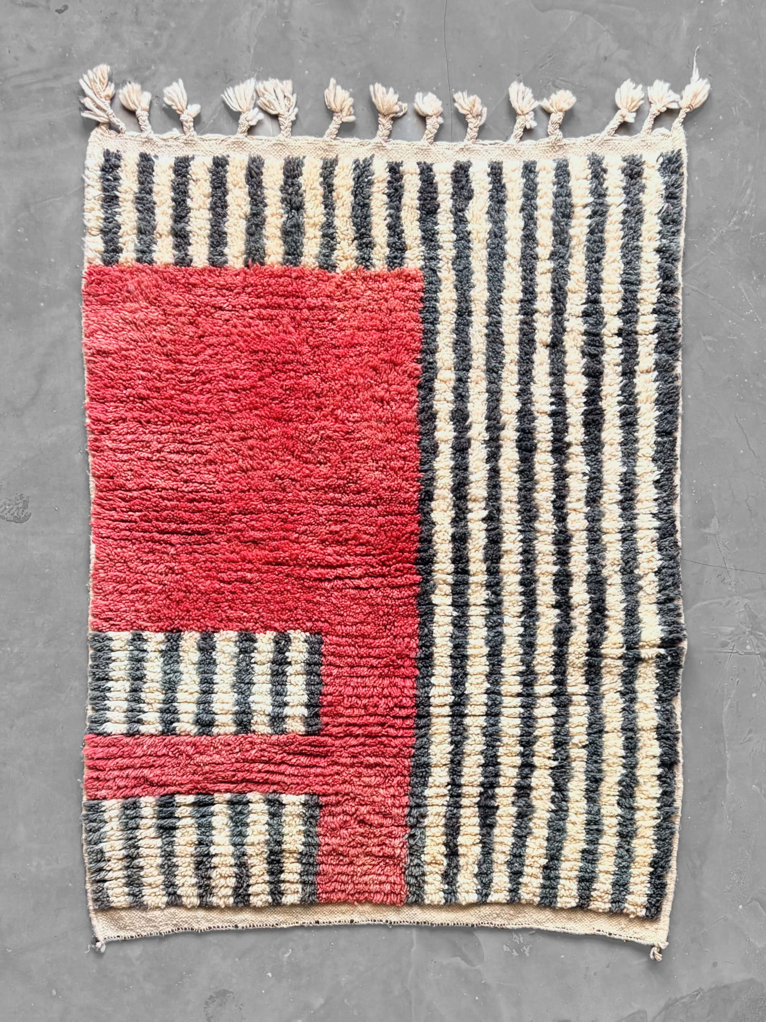 Alfombra marroquí Boujad con bloque rojo y rayas verticales gris antracita y crema, flecos con borlas, vista general desde arriba