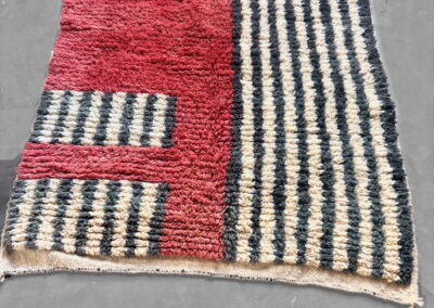Vista en perspectiva de alfombra Boujad roja con rayas gris antracita y crema